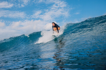 Surfer woman on surfboard during surfing. Surfer girl pop up on breaking wave