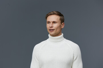 Fototapeta premium Caucasian man wearing white turtleneck sweater look aside smiling studio portrait gray background work mental health gadgets concept