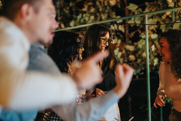A lively group of friends laughing and spending time together during an evening party held...