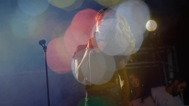 Female singer holding microphone and singing on music stage, with animated colorful bokeh lights