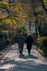 Naklejka premium Elderly couple holding hands walking on stone path in autumn park. Love and longevity concept.