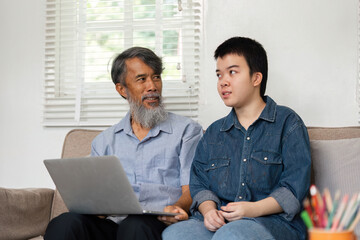 Obraz premium Family Bonding and Technology. A caring grandfather and his grandchild with Down syndrome engaging in a meaningful conversation while using a laptop.