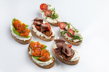 sandwiches with salmon and cheese, meat and tomatoes on a white background