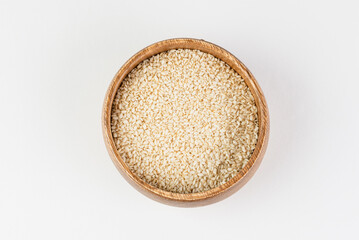 Top view of white sesame seeds in wooden bowl on white background isolated