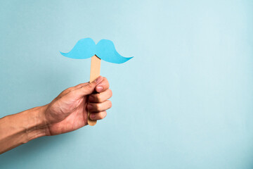 Male Hand holding blue mustache supporting prostate cancer awareness month and men's health