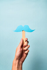 Male Hand holding blue mustache supporting prostate cancer awareness month and men's health