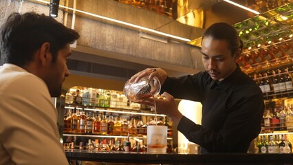 Bartender squeezing orange peel smelling over glass cocktail whiskey putting into Old fashioned on...