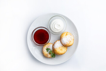 Cottage cheese pancakes with sour cream and jam on a white background