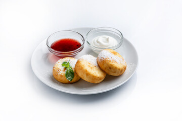 Cottage cheese pancakes with sour cream and jam on a white background