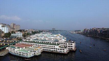 Dhaka is located on the banks of the Buriganga river. Aerial view of Sadar Ghat and the Buriganga river with modern cityscape and boats, Dhaka, Bangladesh.