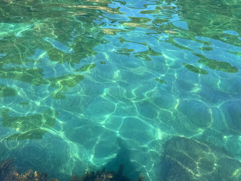 Crystal clear sea water surface with sunlight reflection.
