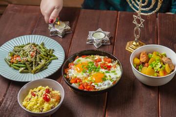 A Jewish woman lights Shabbat candles at a festive table