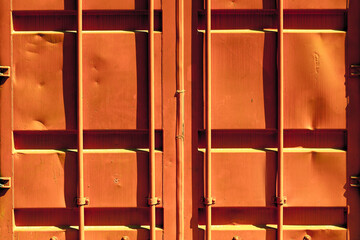 Rusty orange freight container doors with vertical bars and weathered surface