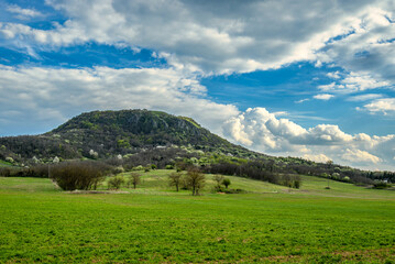 Green spring fields and volcanic hill under dramatic clouds
