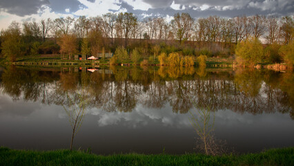 Panorama of the landscape near the pond. Spring, bright landscape along the lake. The middle zone of Ukraine in bloom. Territory of recreation in the countryside. Fishing places.
