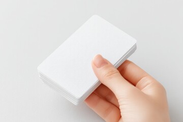 minimalistic image displaying hand holding deck of playing cards against plain white background