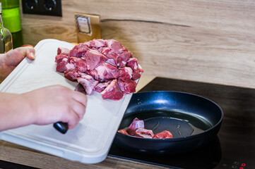 A woman's hand lays out meat in a frying pan for roasting. Recipe for cooking step by step. Pilaf recipe in pictures.