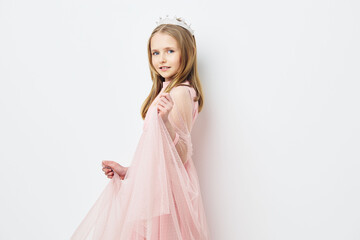 Young girl in a pink dress posing against a white background, showcasing innocence and playfulness...