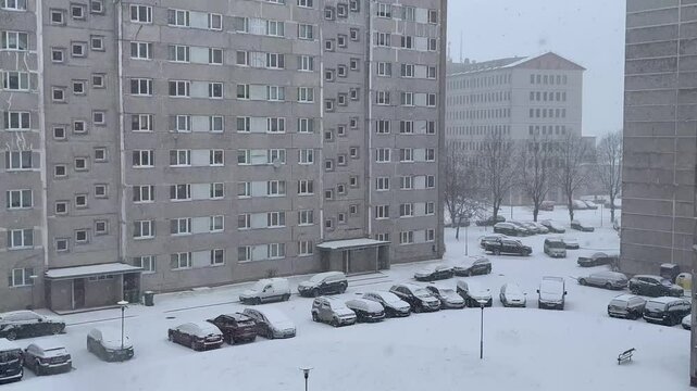 Snowstorm covers Soviet-era residential buildings and parked cars in Ventspils city during late winter