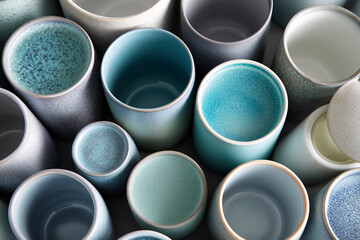 Overhead shot of ceramic cups in various shades of blue and gray, showcasing textured surfaces and empty interiors, suggesting tranquility and minimalism