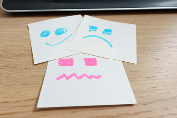 Faces drawn by hand jachated in white notes that represent several emotional states: smiling,...