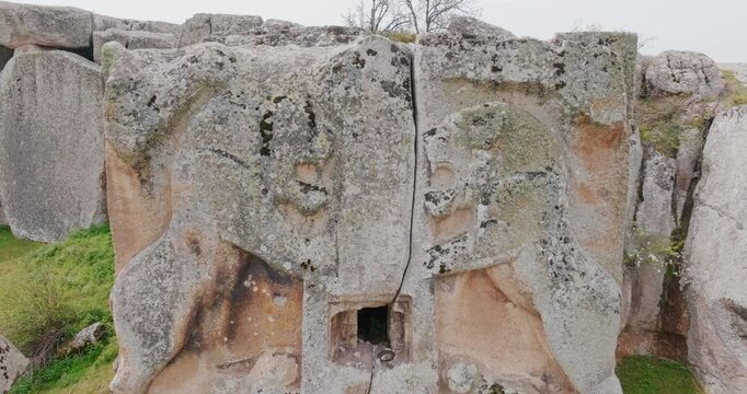 The impressive reliefs at the Historical Aslantaş Monument in Afyon are presented within the rock formations in a wider perspective as the drone slowly zooms out.