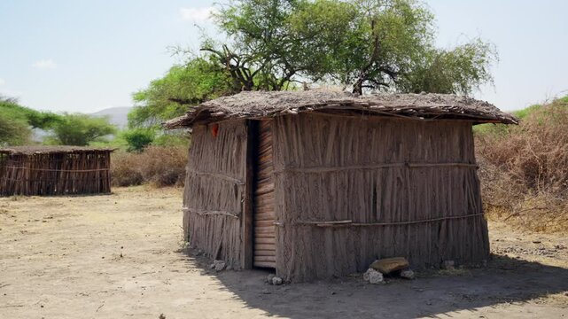 Traditional rustic African hut with thatched roof and mud walls in Maasai tribe. Typical house made by local community of Masai people native to Tanzania land. Connection to nature with simple living