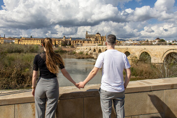 young couple holding hands looking out at cityscape