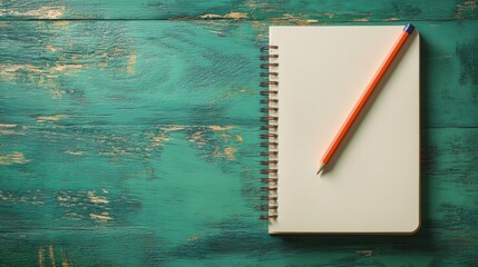 Blank spiral notebook with orange pencil on rustic teal wood background.