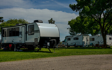Camper trailer on grass with cloudy sky and other campers