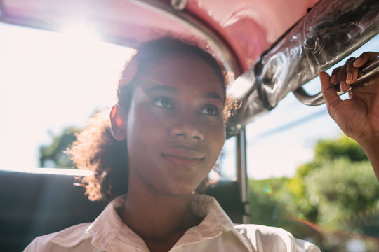 black traveling girl bored hot riding tuk tuk car on vacation. young african american tourist sitting exhausted Auto rickshaw ride. tired solo tourist girl sitting on transportation seat on sunny.
