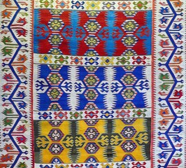 Vibrant geometric patterns weaving cultural heritage through red, blue, yellow hues on traditional carpet surface
