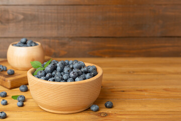 Bowl with fresh blueberries on wooden table