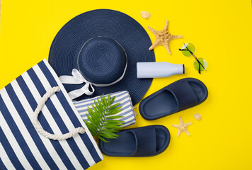 Blue beach bag with summer accessories on color background, top view