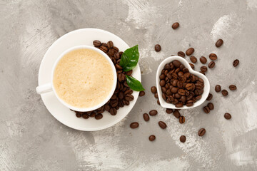 Cup of coffee with coffee beans and leaves on concrete background,top view