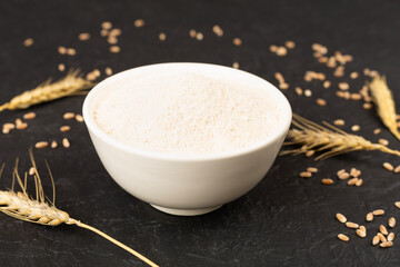 Bowl with spelt flour on wooden table