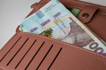 Wallet with Ukrainian hryvnia, coins and banknotes on white table. Personal finance, money savings, cash payment, financial planning, economy concept.