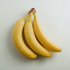Three ripe yellow bananas on a white surface