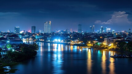 Night city skyline reflected on calm river. Urban lights illuminate modern high-rise buildings and historic architecture along a tranquil waterway