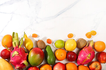 Dragon fruit, pitaya, mango, kiwi, avacado, apples, citrus and dried apricots on a sunny table. Banner with tropical exotic fruits and juice with space for text. Healthy vegan food for weight loss