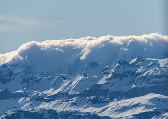 Obraz premium Majestic snow-capped mountains under a cloud-covered sky in a serene landscape during midday