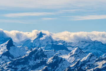 Majestic snowy mountains under a clear blue sky with wispy clouds in the distance during midday sun