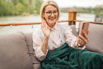 mature woman sit on the terrace use mobile phone talk on video call