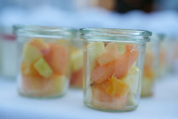 Colorful fruit salad in glass jars arranged on a table, highlighting fresh and healthy dessert options for catered events.