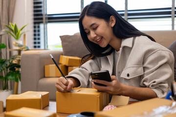 A woman is holding two boxes and smiling. She is sitting in front of a laptop. The boxes are brown and appear to be gifts. The woman seems happy and excited about the boxes
