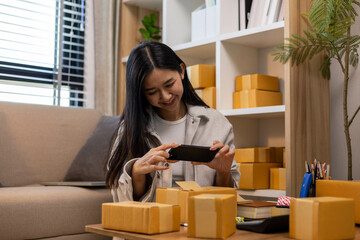 A woman is holding two boxes and smiling. She is sitting in front of a laptop. The boxes are brown and appear to be gifts. The woman seems happy and excited about the boxes
