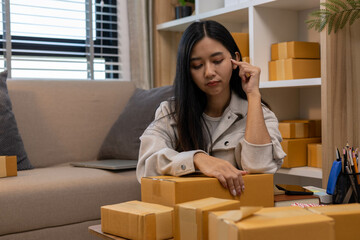 A woman is holding two boxes and smiling. She is sitting in front of a laptop. The boxes are brown and appear to be gifts. The woman seems happy and excited about the boxes
