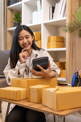 A woman is holding two boxes and smiling. She is sitting in front of a laptop. The boxes are brown and appear to be gifts. The woman seems happy and excited about the boxes
