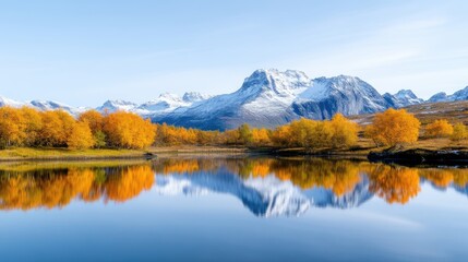 Autumnal lake reflecting snow-capped mountains.  Golden trees line the tranquil water's edge