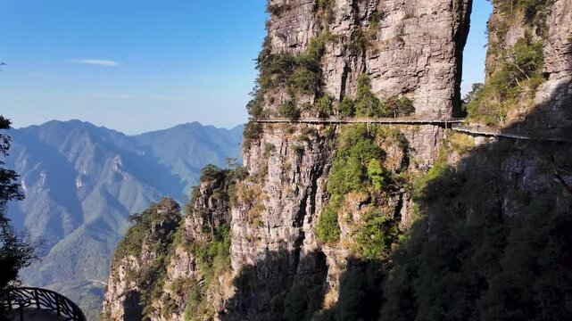 Walking trail along a beautiful natural mountain landscape in Southern China, featuring rugged cliffs and towering rock formations rising from a forested valley. Jinxiu, Guangxi, China
